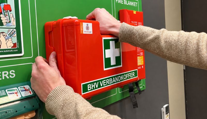 BHV-verbandkoffer wordt van de wand gehaald bij een deur